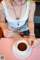 A woman sitting at a table with a cup of coffee.