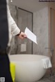 A person holding a piece of paper in a bathroom.