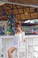 A woman sitting on a white chair in front of a bar.