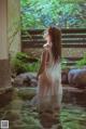 A woman in a white dress standing in a pool of water.