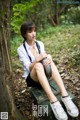 A woman sitting on a wooden bench in the woods.