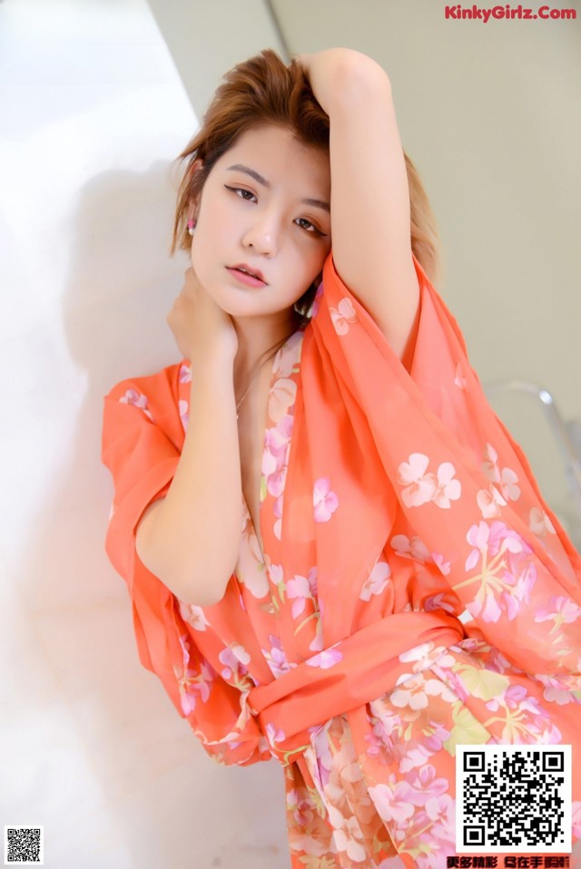 A woman in an orange kimono posing for a picture.
