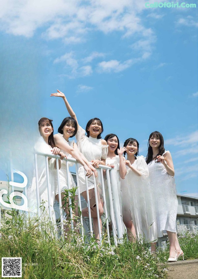 A group of women standing next to each other in front of a fence.