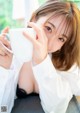 A woman in a white shirt is holding a cup of coffee.